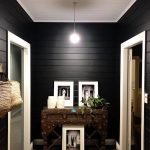 Hallway with black painted walls, pendant light, and framed photos.