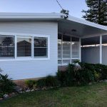 White weatherboard house exterior with covered patio and garden landscaping.