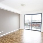 Empty room with timber flooring, feature wall, and glass sliding door to balcony.