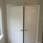 White double doors with silver handles in a neutral painted room.