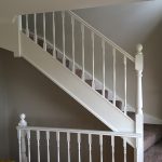 Indoor staircase with white railing and carpeted steps.