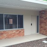 House entrance with brick walls, large front window, and beige door.