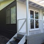 Small house with black and white cladding, front porch, and steps.