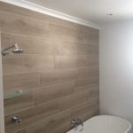 Modern bathroom with freestanding bathtub and tiled feature wall.