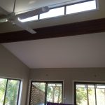 Living room with high ceiling, ceiling fan, and large windows.