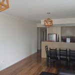 Dining area with black table and chairs, wooden flooring, and modern kitchen.