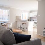 Modern open-plan living area with sofa, kitchen, and dining nook.